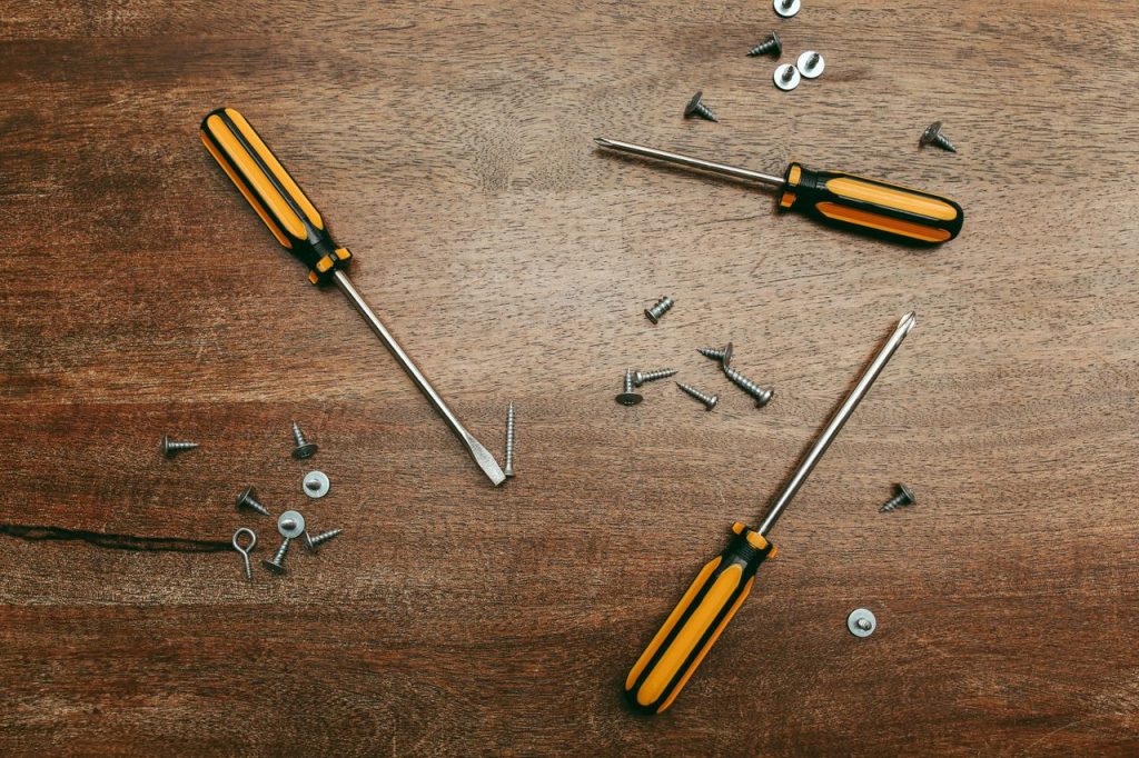 Flatlay of screwdrivers and screws on a wooden table, perfect for carpentry themes.